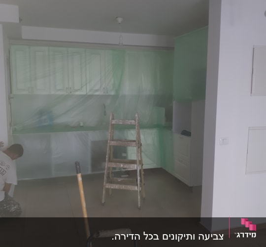 סולם וחיפוי פלסטיק על ארונות מטבח לצביעת קירות